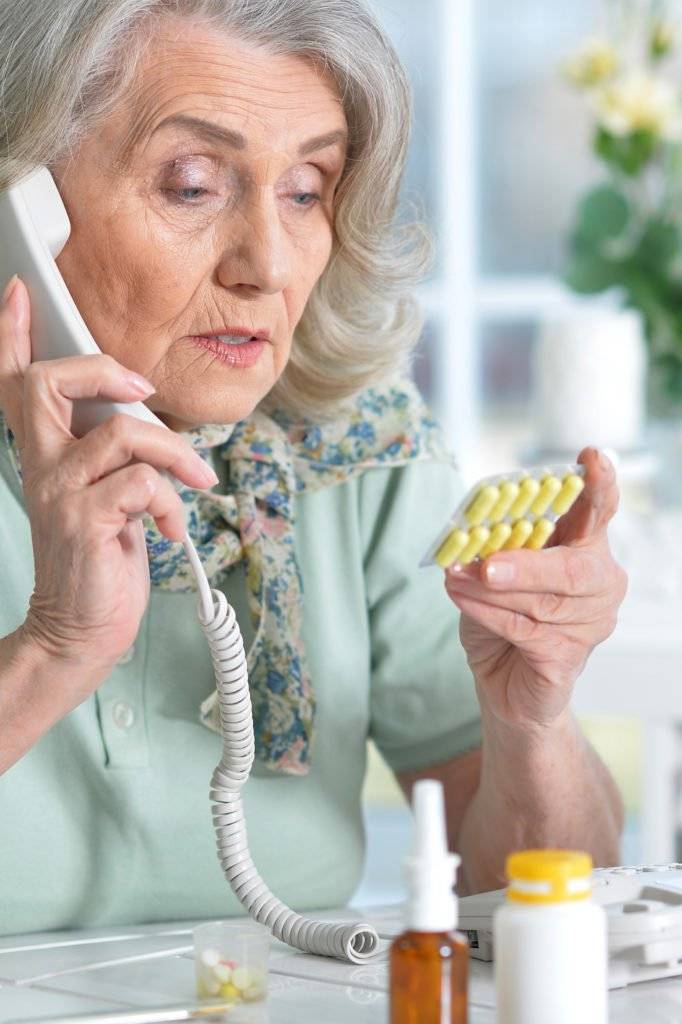 Portrait of sick senior woman sitting at table