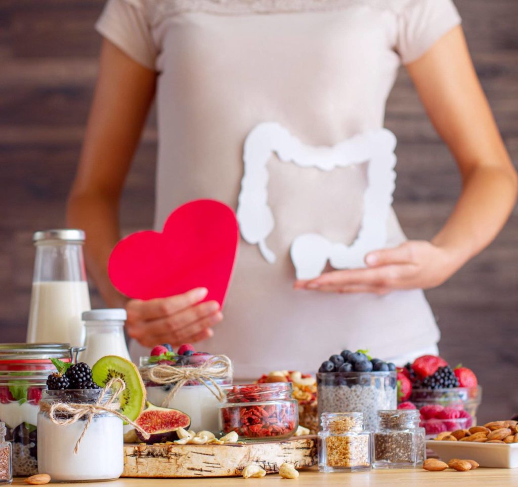 Female is holding figures of heart and intestines. Summer breakfast with organic yogurts fruits, berries and nuts. Nutrition that promotes good digestion and functioning of gastrointestinal tract.