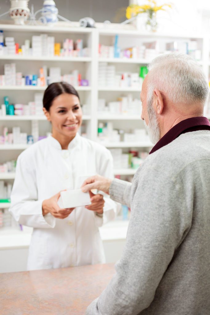 Apotheker*In und Kunde stehen an der Theke. Apotheker*In berät den Kunden zu Medikamenten. Karriere in der Borromäus Apotheke Salzburg, Parsch.